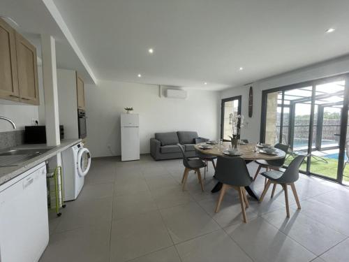 a kitchen and living room with a table and chairs at Gîte rénové avec piscine chauffée couverte, climatisation, proche randonnées et attractions locales - FR-1-489-471 in Couzon