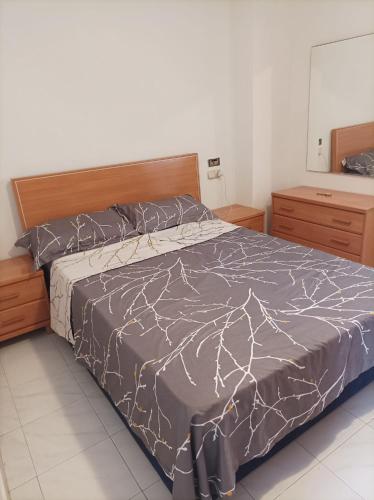 una camera da letto con un letto con un piumone grigio di Appartement l’escala a L'Escala