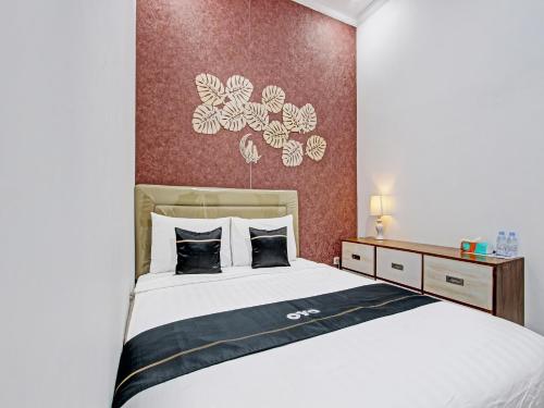 een slaapkamer met een groot wit bed met zwarte kussens bij Capital O 92895 House N Caffe 55 in Temanggung
