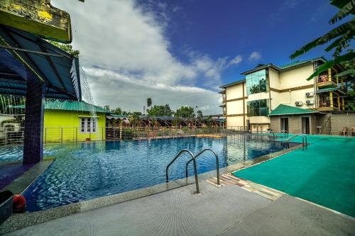 a large swimming pool in front of a building at Resort Trimurti in Chālsa Mahābāri