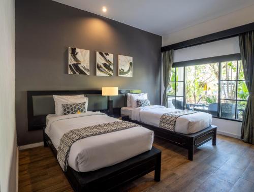 a bedroom with two beds and a window at Casa Wina Kuta in Kuta