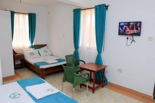 a room with two beds and a table and a couch at Greenyard Resort Mtwapa in Mtwapa