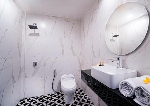 a bathroom with a sink and a toilet and a mirror at Casa Wina Kuta in Kuta