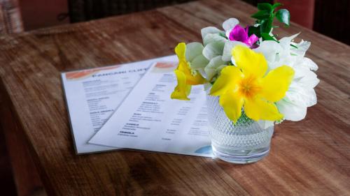 a vase of flowers on a table with a menu at Pangani Cliffs Lodge in Pangani