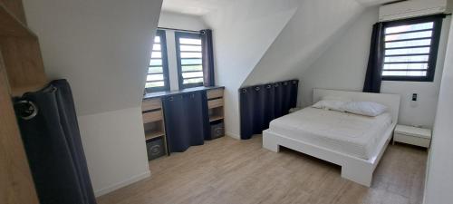 1 dormitorio con 1 cama y 2 ventanas en Les Pieds Dans l'Eau face à la mer des caraïbes Jacuzzi Sainte-Luce Trois-Rivières, en Sainte-Luce