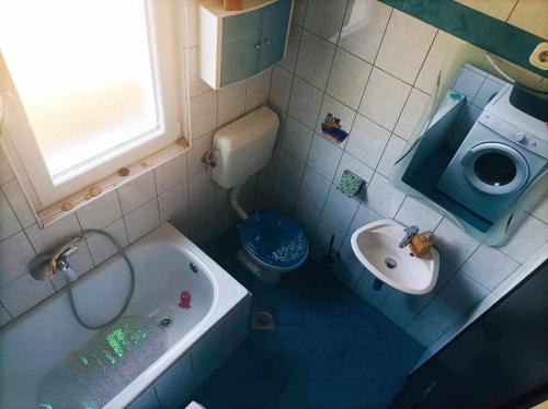 a bathroom with a sink and a tub and a toilet at Apartman MR in Potpićan