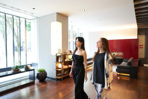 two women standing in a living room looking at each other at Hotel Resol Trinity Kanazawa in Kanazawa