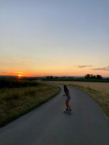 a young girl riding a skateboard down a road at Wohnen am Wasserschloss Sandizell in Schrobenhausen