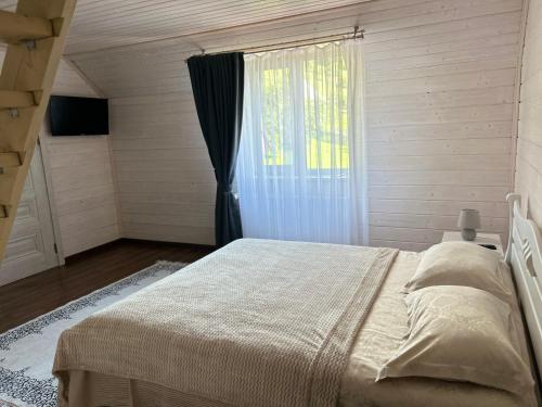 Un dormitorio con una cama grande y una ventana en Вілла Смерекова хата - Келечин 144 en Pilipets