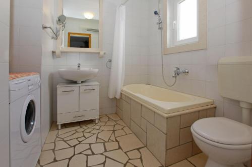 a white bathroom with a sink and a toilet at Apartments Mel in Bol