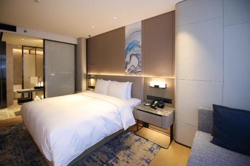a bedroom with a large white bed and a desk at Courtyard by Marriott Shenzhen Northwest in Bao'an