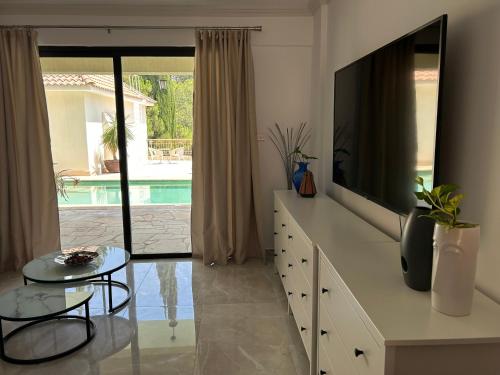 a living room with a flat screen tv and a table at Luxury Kouklia Apartments in Kouklia
