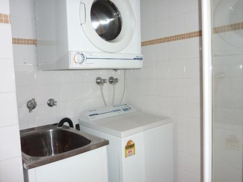 Il comprend une petite cuisine avec un évier et un lave-linge. dans l'établissement Contemporary Apartment, à Sydney