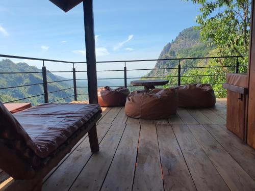 a wooden deck with a couch and a table on a mountain at Ella Mount View Guest Inn in Ella