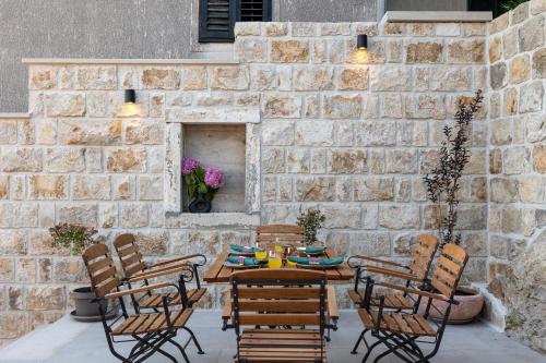 a patio with a table and chairs and a stone wall at Holiday Home Nico's in Cavtat