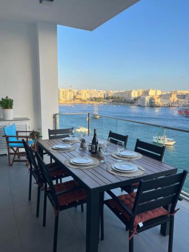 - une table à manger avec des chaises et une vue sur l'eau dans l'établissement Seafront Two Bedroom Apartment, à San Ġiljan