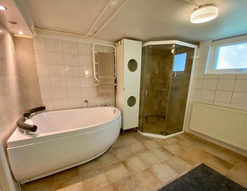 y baño con bañera grande y ducha. en Lower floor of 50 sqm in nice villa with parking, en Estocolmo