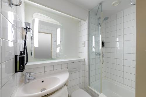 een witte badkamer met een wastafel en een douche bij Ibis Hotel Köln Am Dom in Keulen