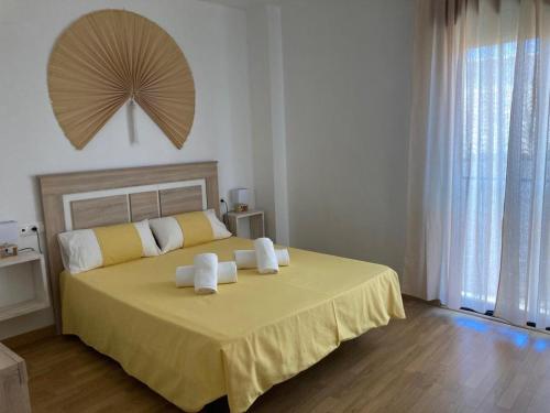 Un dormitorio con una gran cama amarilla con toallas. en Casco Antiguo PONDOS, en Linares