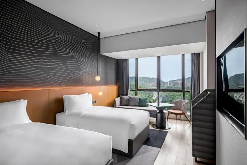 a hotel room with two beds and a tv at The G Shenzhen, A Tribute Portfolio Hotel in Shenzhen
