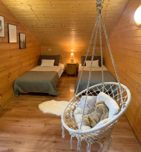 Cette chambre comprend deux lits et une balançoire avec un ours en peluche. dans l'établissement Oreeduloup Chalet Grand Loup 14/16 pers., à Saint-Étienne-en-Dévoluy