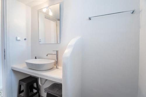 a white bathroom with a sink and a mirror at Kefos Apartments Paros in Kóstos