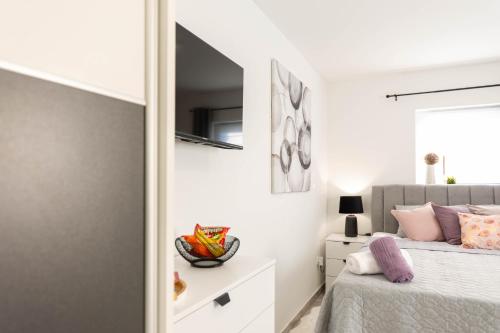 a white bedroom with a bed and a mirror at apartmani SUN & MOON in Bjelovar