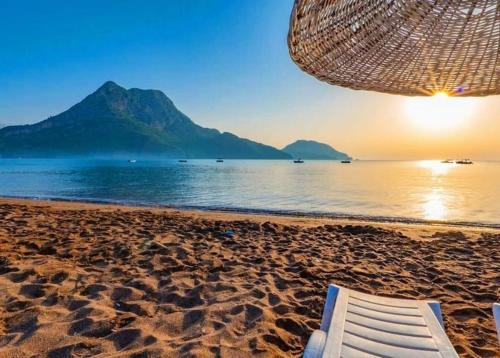 a beach with an umbrella and a chair on the sand at ZEYOS LODGE HOTEL&RESTAURANT in Kumluca