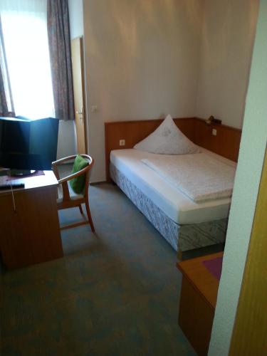 a bedroom with a bed and a desk and a television at Landhotel Wilhelm Busch in Lüthorst