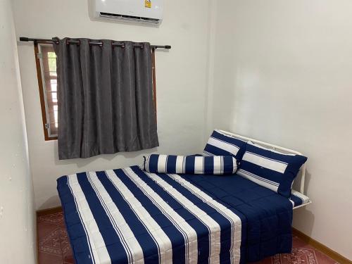 1 dormitorio con 1 cama con rayas azules y blancas en ศรีวดีโฮม(Sriwadee Home), en Ban Phai