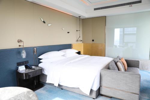 a bedroom with a large bed and a couch at Hilton Yancheng in Yancheng