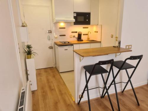 cocina con 2 sillas y barra en una habitación en Très beau studio au pied du métro en Vincennes