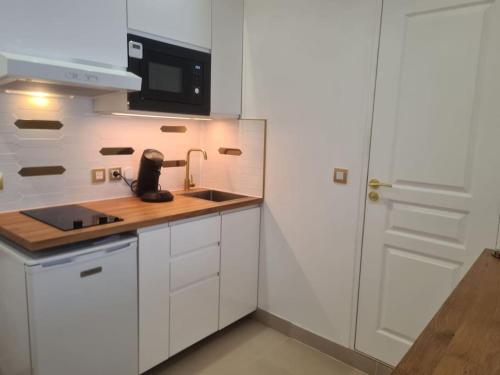 a white kitchen with a sink and a microwave at Très beau studio au pied du métro in Vincennes