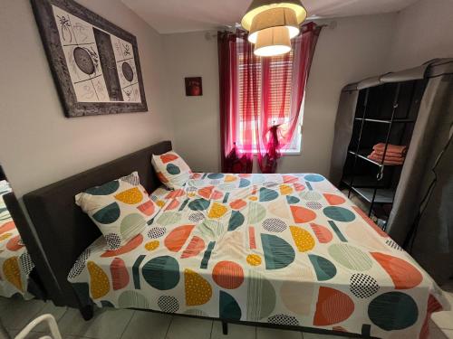アンネヴィルにあるPôle Thermal & Touristique Amnévilleのベッドルーム1室(カラフルな掛け布団付きのベッド1台付)