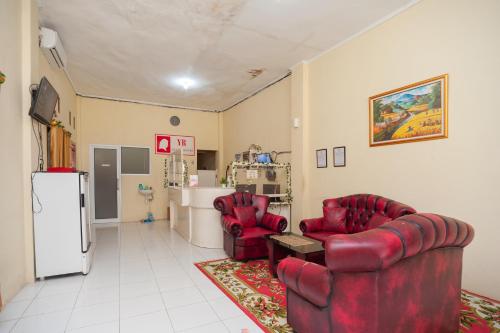 a living room with two red chairs and a refrigerator at RedDoorz near Universitas Muhammadiyah Pringsewu in Margakaya