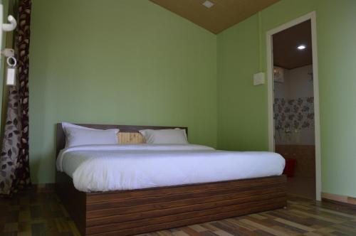 een slaapkamer met een groot bed in een groene muur bij Upvan Guest House and Residence in Bhīm Tāl