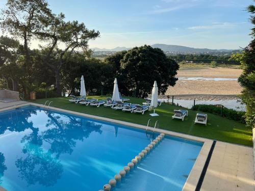 a swimming pool with chairs and umbrellas on a resort at Hotel Olimpo in Isla