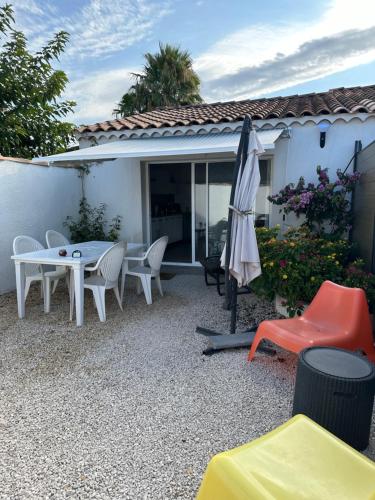 eine Terrasse mit einem Tisch, Stühlen und einem Sonnenschirm in der Unterkunft Cocon en Provence in Marignane