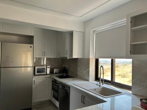 a kitchen with white cabinets and a sink and a window at Luxury Kouklia Apartments in Kouklia
