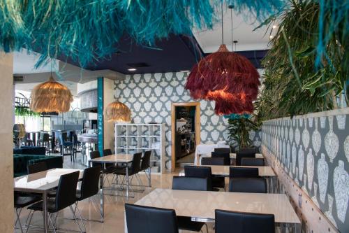 a restaurant with tables and chairs and chandeliers at Hotel Olimpo in Isla