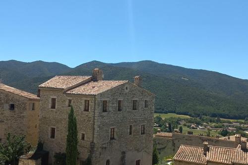 a large stone building with mountains in the background at Vakantiehuis “Le Verbe” in de Drôme Provençale in Le Poët-Laval