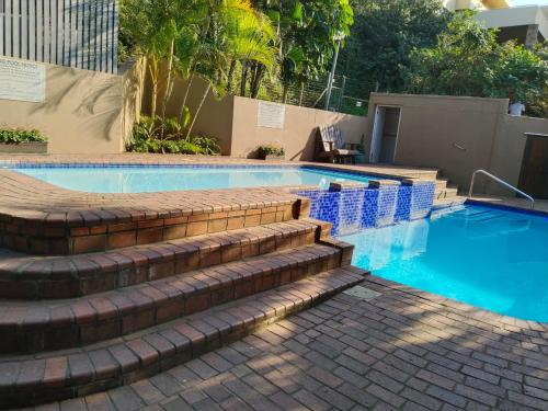 a swimming pool with stairs and blue water at 21 Camarque in Umdloti