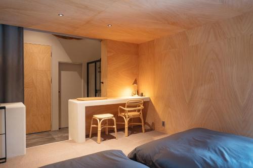 a bedroom with a bed and a desk with two chairs at APARTMENTS by Bed and Craft in Inami