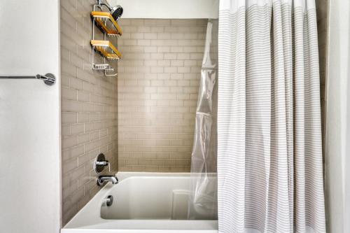uma banheira branca na casa de banho com uma cortina de chuveiro em Downtown 1br w gym wd pool nr Capitol ATX-83 em Austin