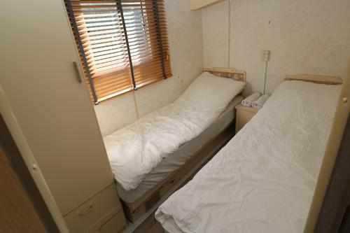 2 camas en una habitación pequeña con ventana en De Zuidvliet Chalet 2, en Wolphaartsdijk