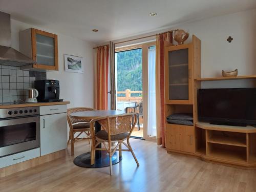 een keuken met een tafel met stoelen en een televisie bij Ferienwohnung Egger in Prägraten