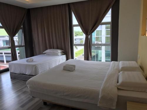 two beds in a bedroom with a large window at TOWERMAS HOTEL in Sibu