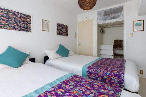 2 camas en una habitación con paredes blancas en Haleakala Hotel, en Asato