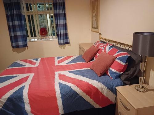 a bed with a red white and blue blanket at Large countryside home in Tow Law