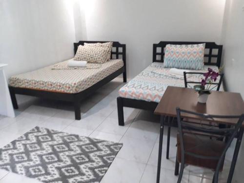 Habitación con 2 camas, mesa, mesa y sillas. en JOCANAI RESIDENCES Furnished Private Room, en Lusong